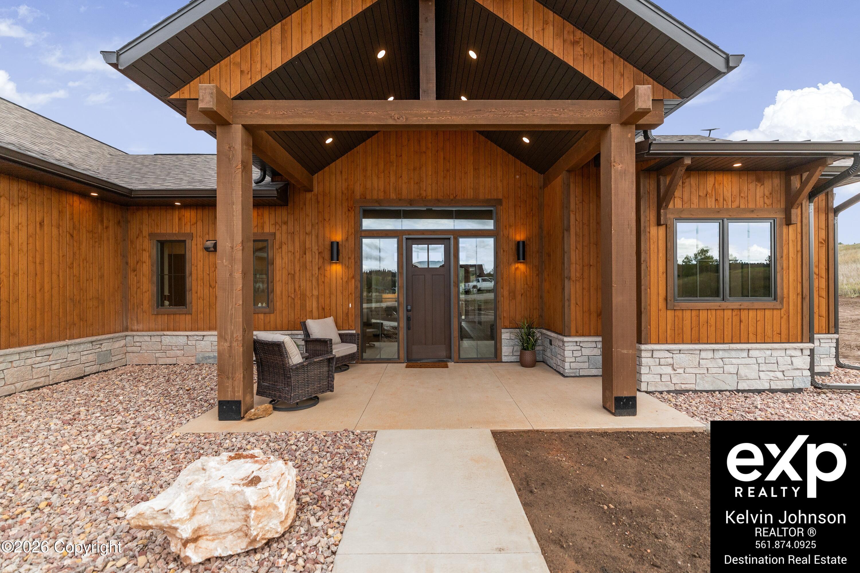 Wood-sided home with stone base and a tall timber-covered front porch.