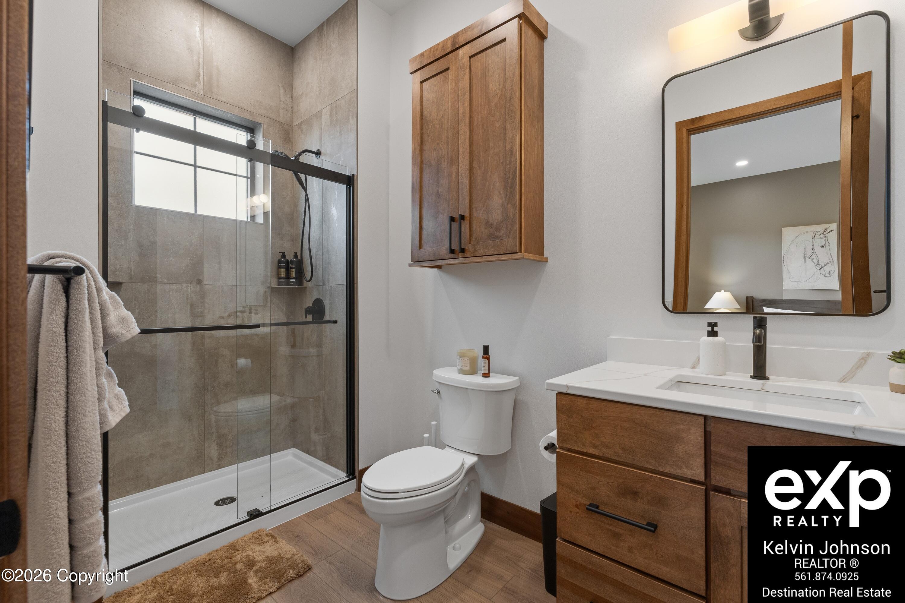 Bathroom with a glass walk-in shower, gray tile, and a wood vanity.