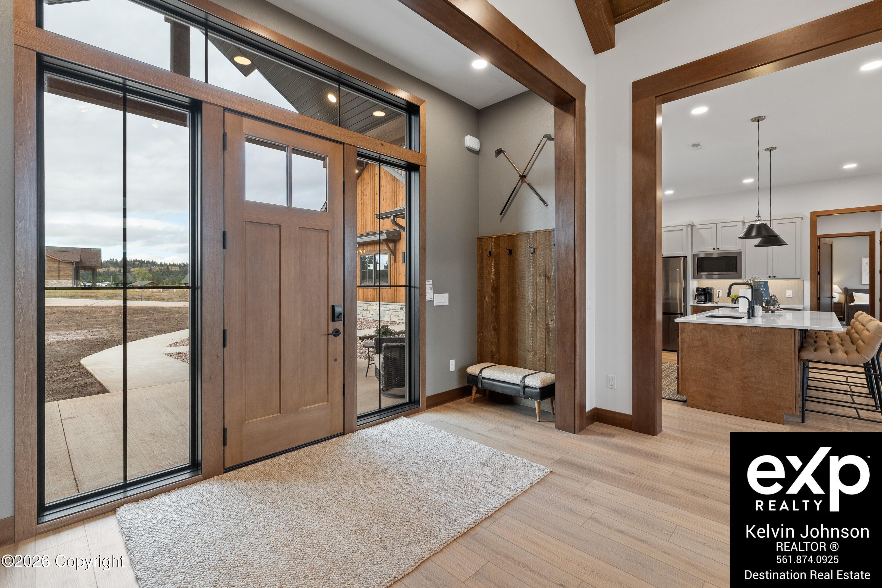 Entryway with a wood front door, tall glass sidelights, exposed beams, and a bench beside the kitchen.