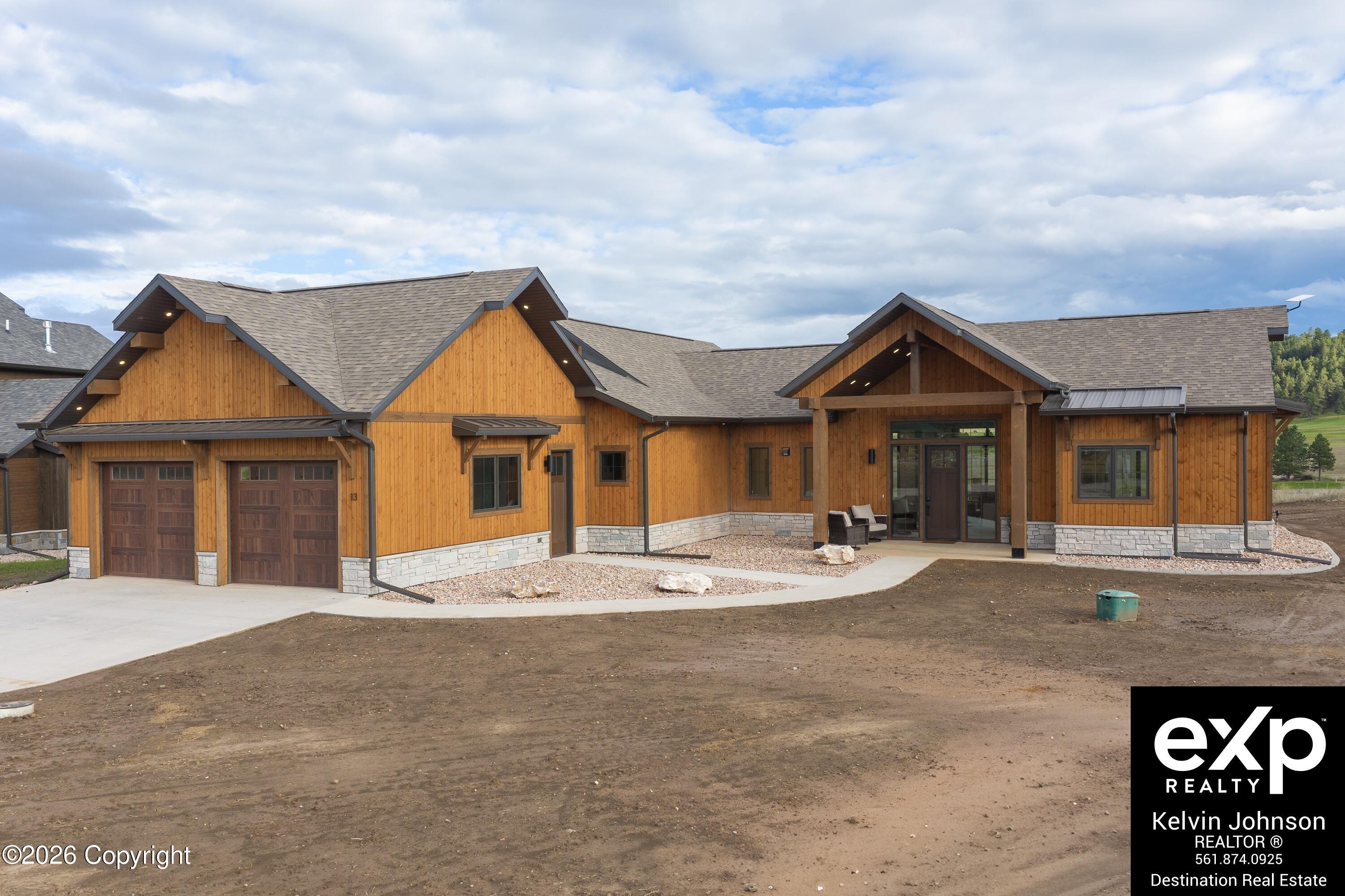 Wood-sided home with stone accents, two-car garage, and covered front entrance.
