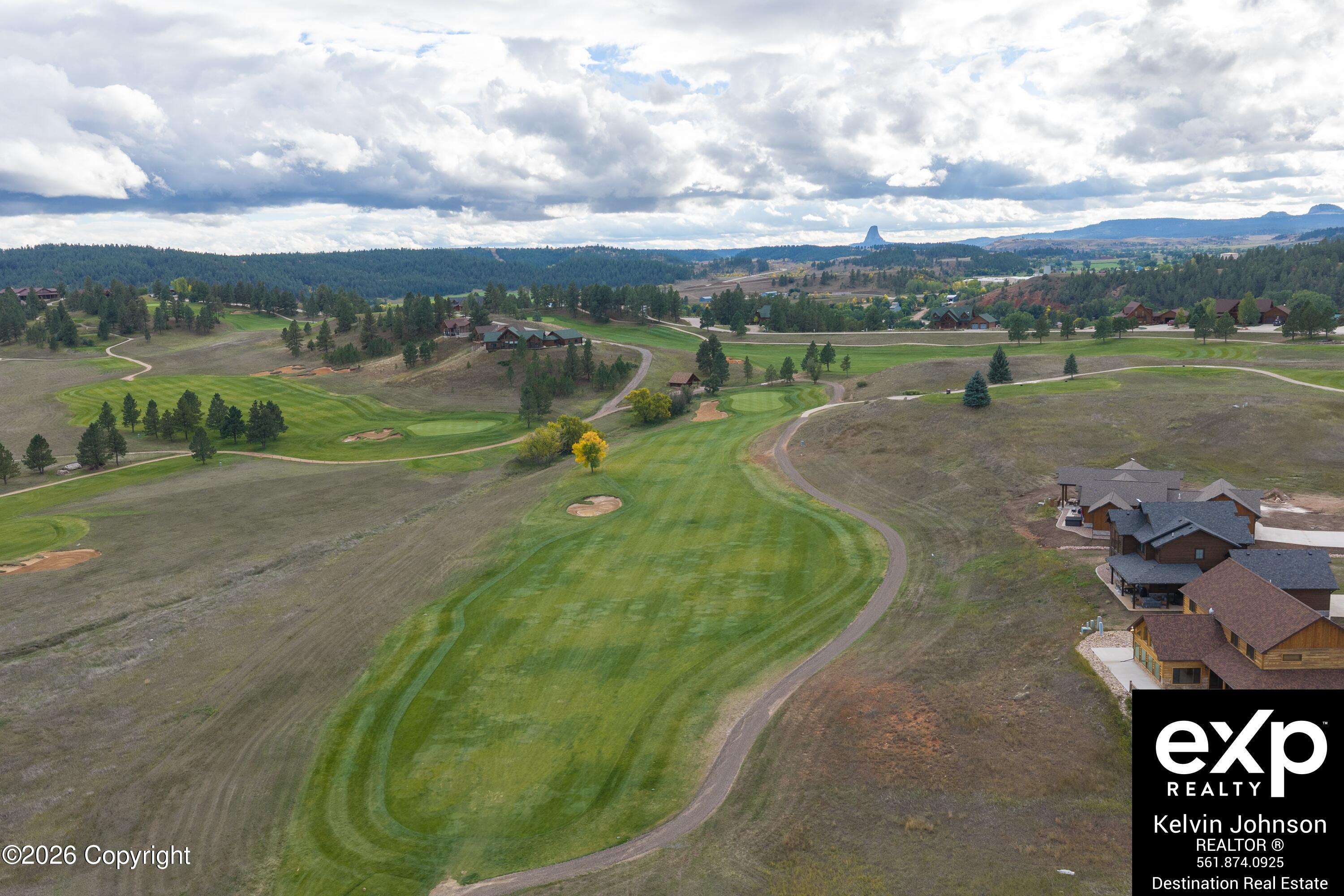 Aerial view of a golf course with homes and Devils Tower in the distance.