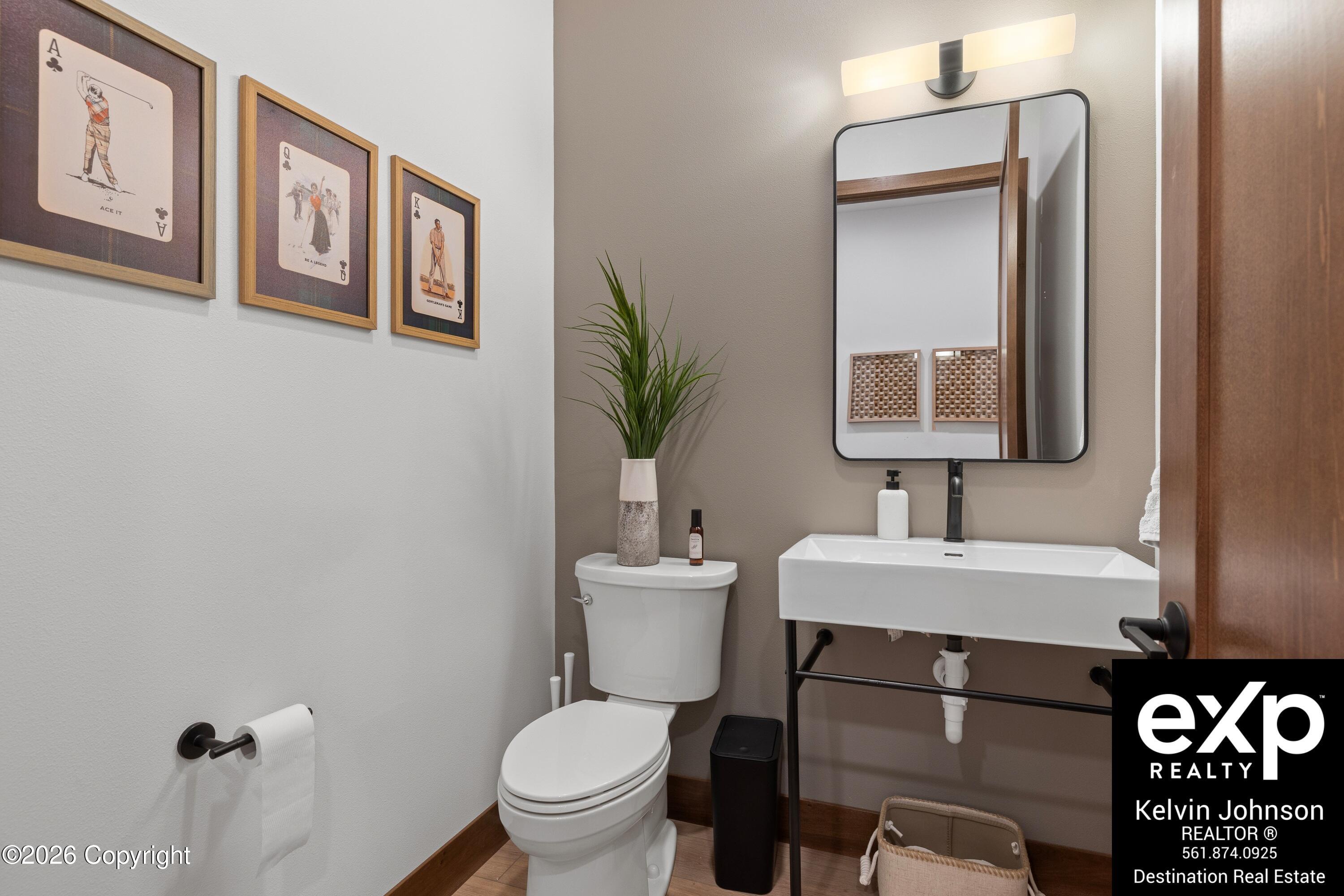 Bathroom with a white sink, black-framed mirror, toilet, and framed golf-themed artwork.