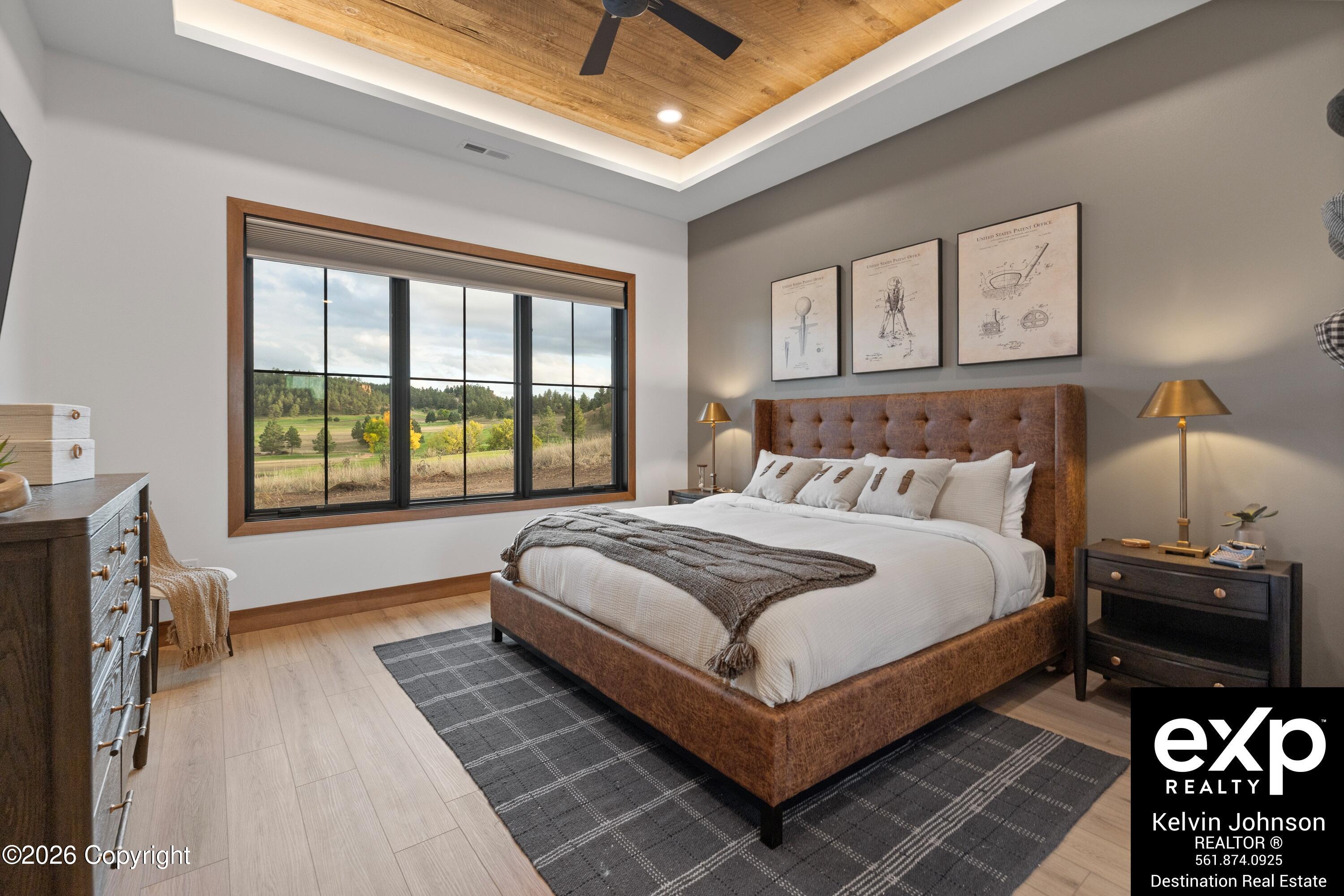 Staged bedroom with a tufted brown bed and wide window overlooking green countryside.