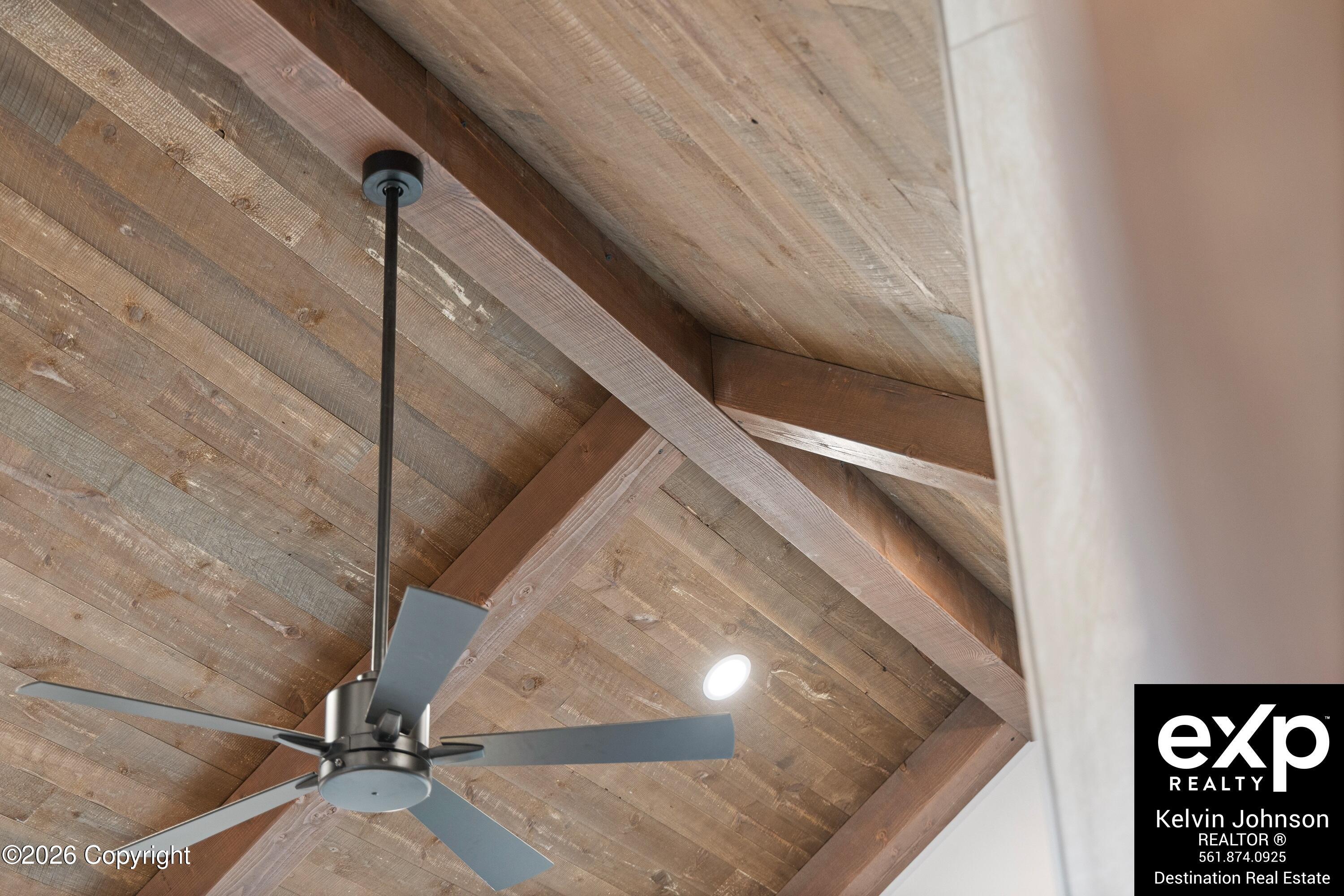 Rustic vaulted wood ceiling with exposed beams, a modern ceiling fan, and recessed lighting.