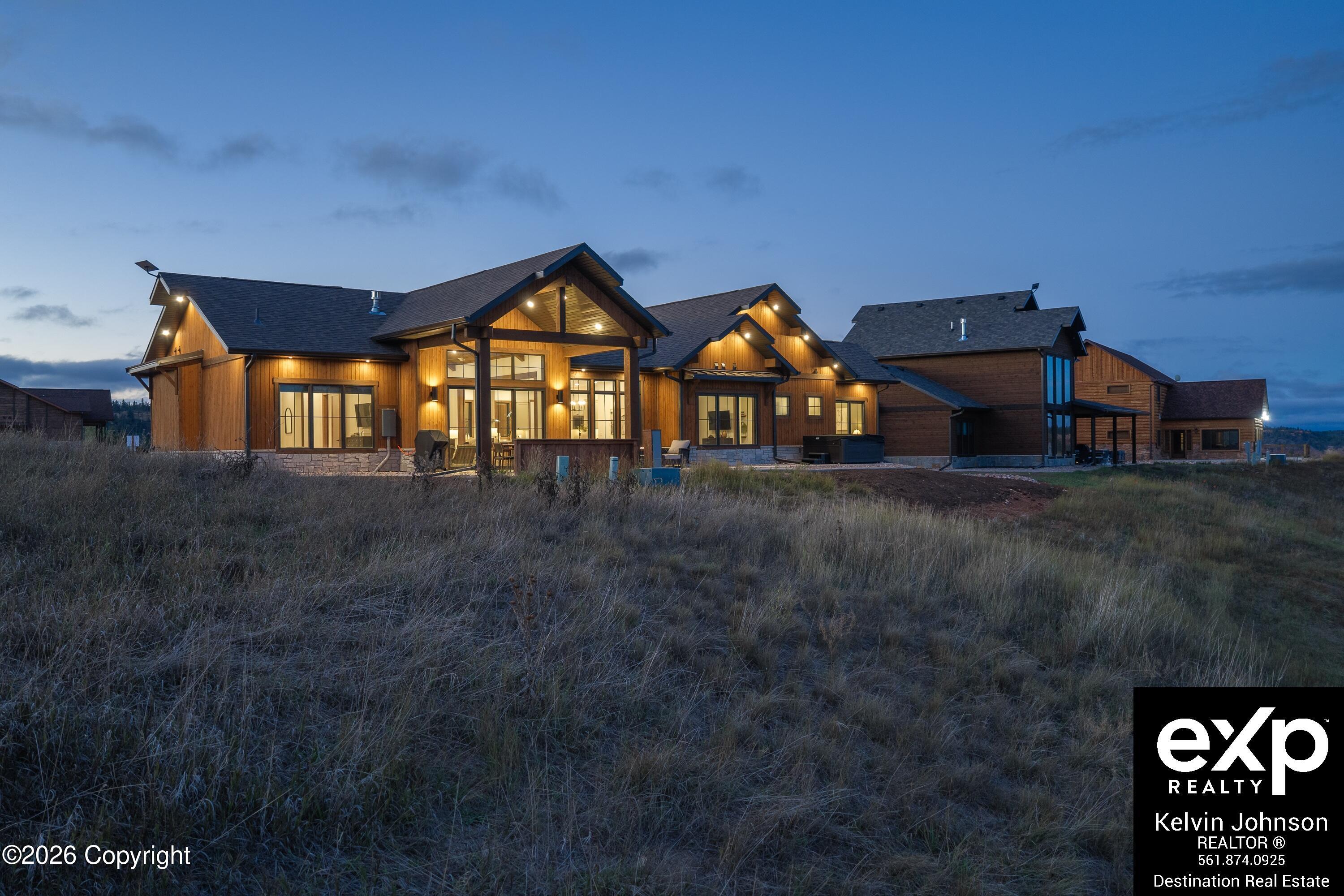 Large wood-sided home at dusk, with warm lights glowing through its windows.