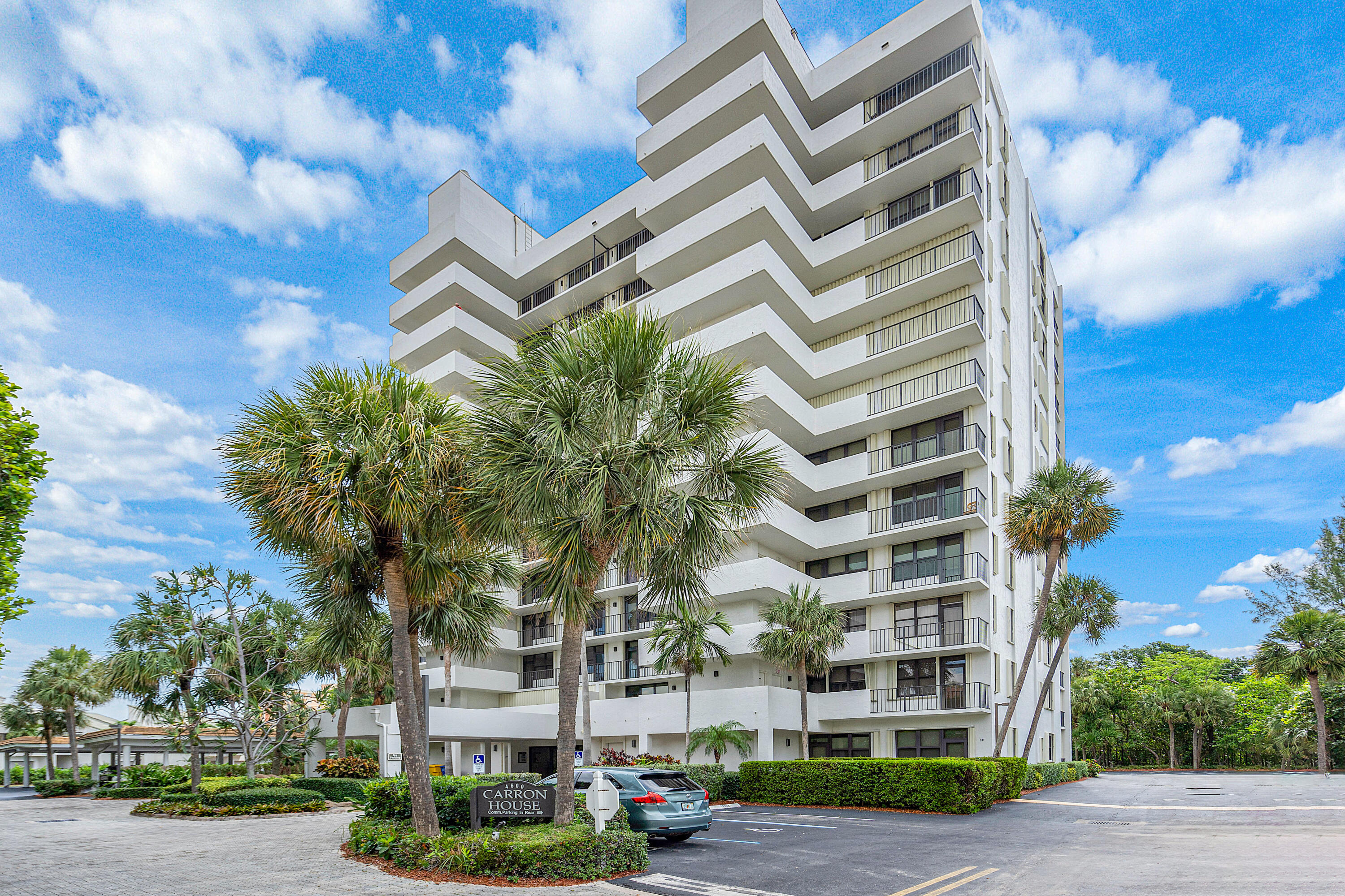 Carron House condominium with zigzag balconies, palm trees, and a landscaped entrance.