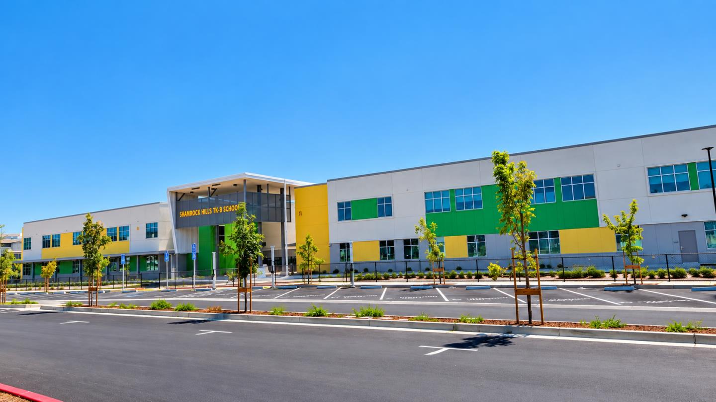 Shamrock Hills TK-8 School with green and yellow panels and a tree-lined parking lot.