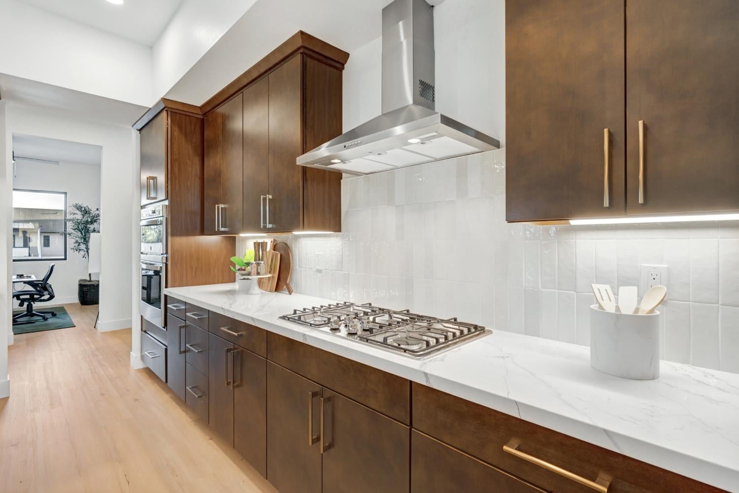 Modern kitchen with dark wood cabinets, a gas cooktop, and white quartz countertops.