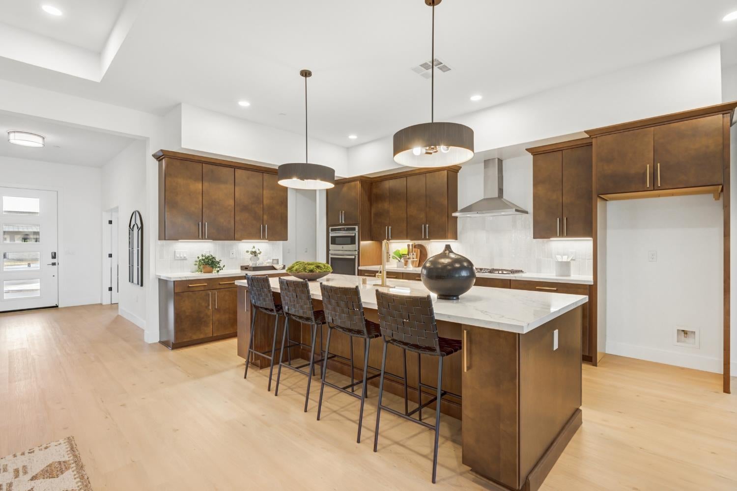Kitchen with dark wood cabinets, a large island, and four bar stools.