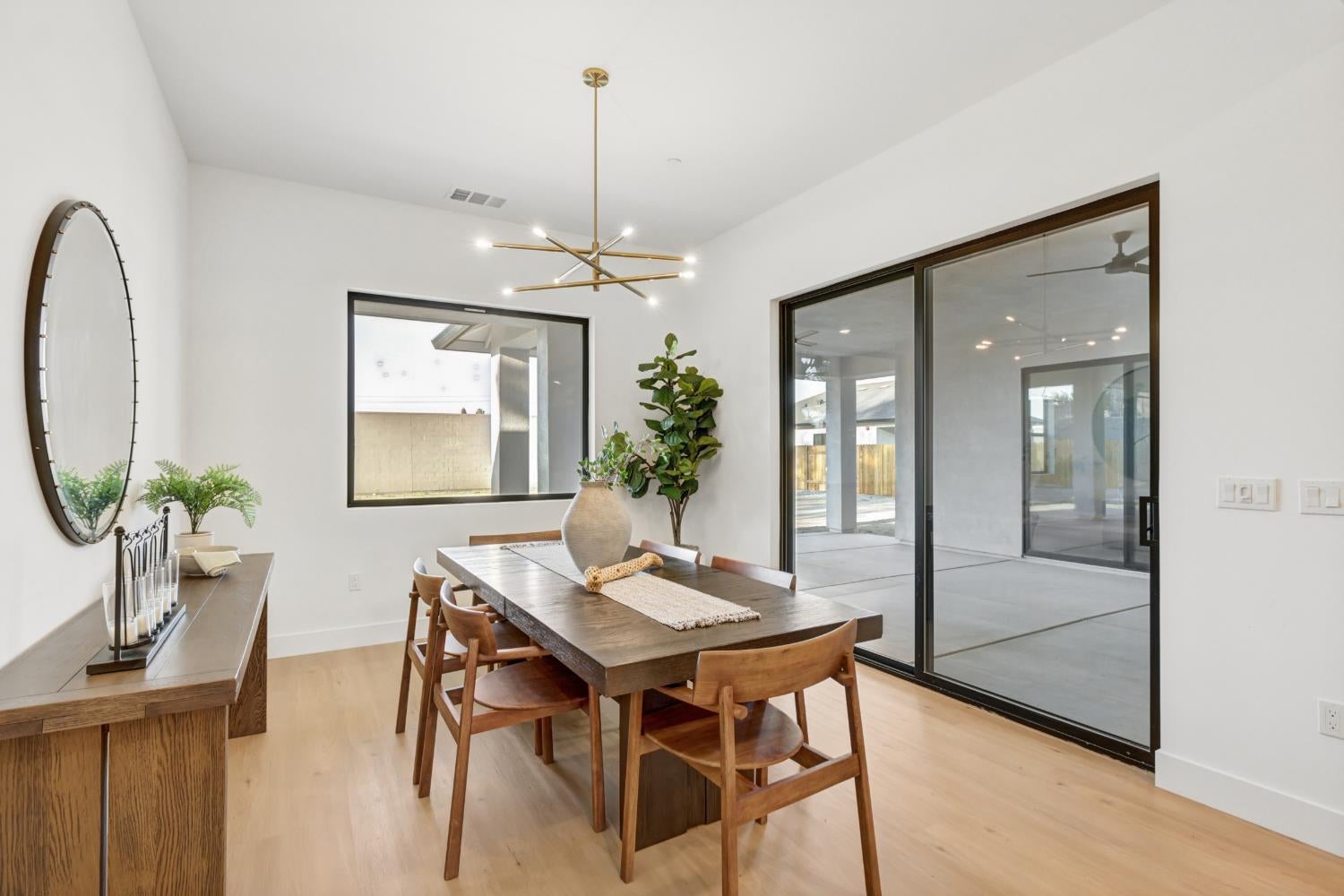 Dining room with a dark wood table, brass chandelier, and sliding glass doors to a covered patio.