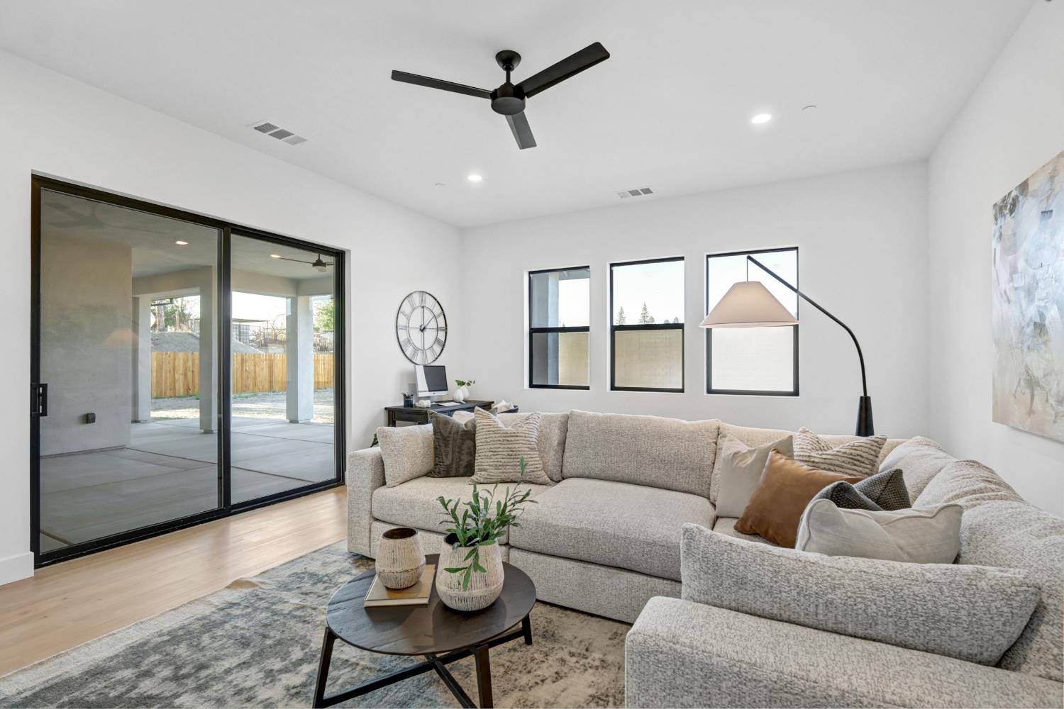 Staged living room with a light-gray sectional and sliding glass doors opening to a covered patio.