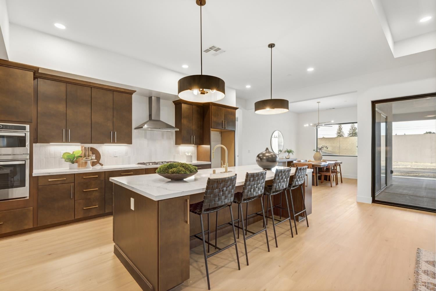 Kitchen with dark wood cabinets, a large white island, bar stools, and an adjoining dining area.