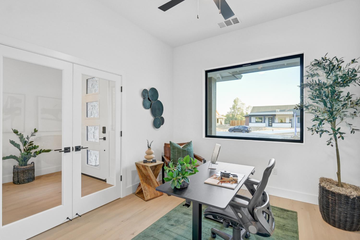 Bright home office with a large window, glass-paneled doors, and a desk with office chairs.