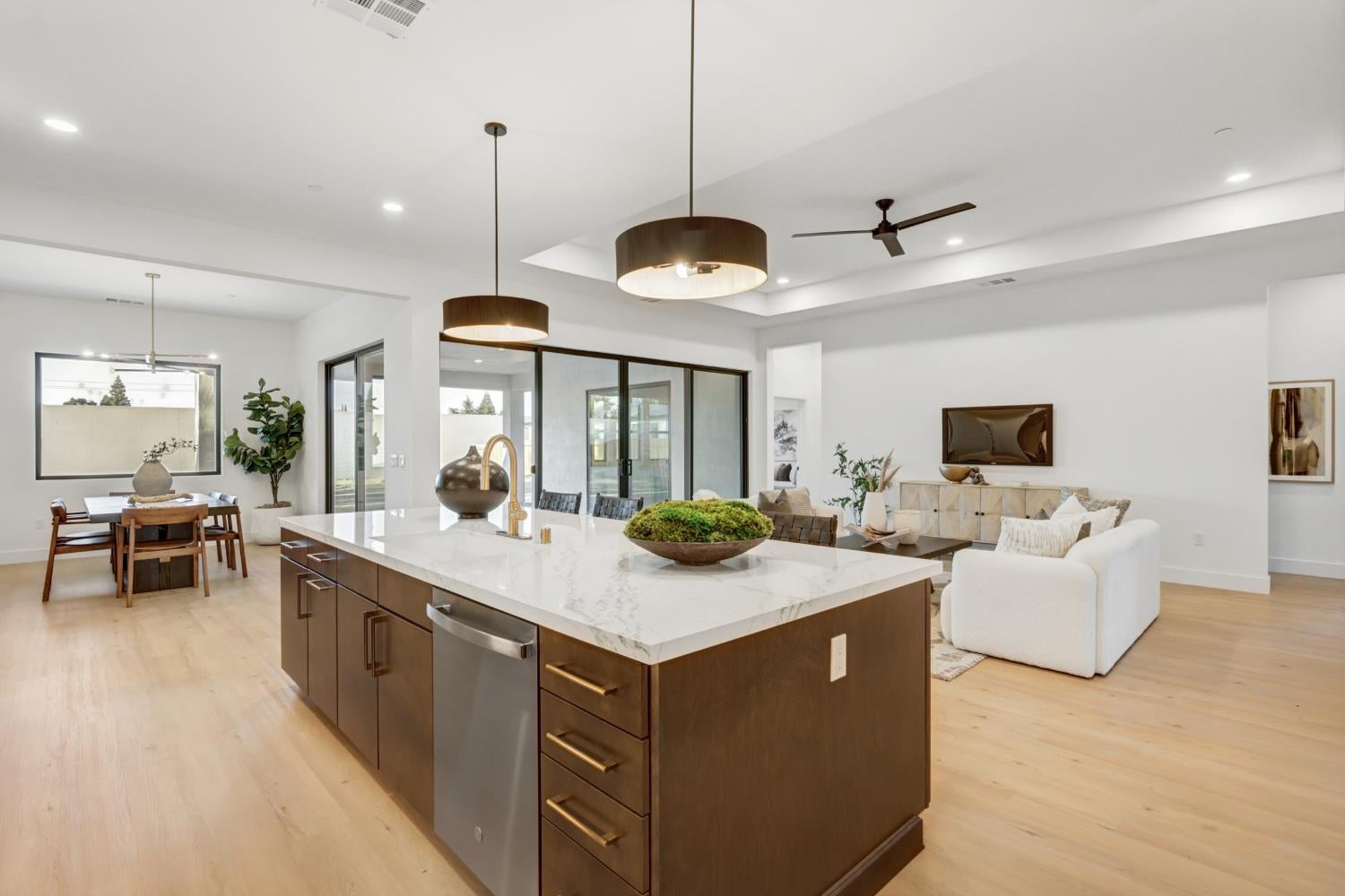Open-plan kitchen with a large marble-topped island, dining area, and living room.