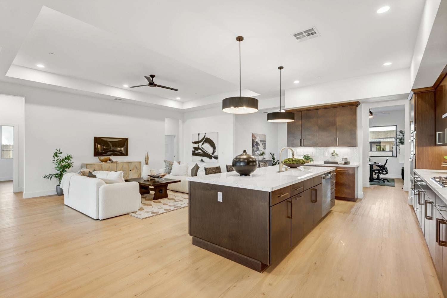 Open-plan kitchen and living area with a large dark wood island and white stone countertops.