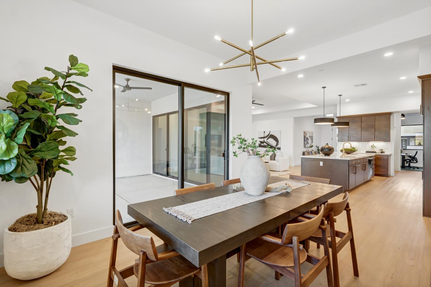 Open-plan dining room with a dark wood table beside a sliding glass door and kitchen island.