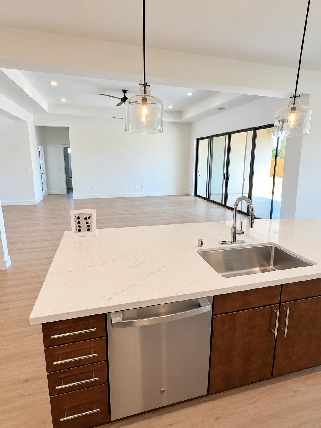 Modern kitchen with a quartz island, dark wood cabinets, and sliding glass doors to the patio.