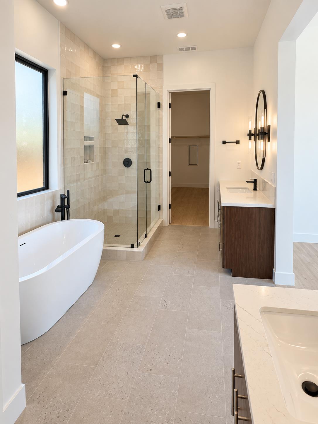 Modern bathroom with a freestanding tub, glass-enclosed tiled shower, and dark wood vanity.