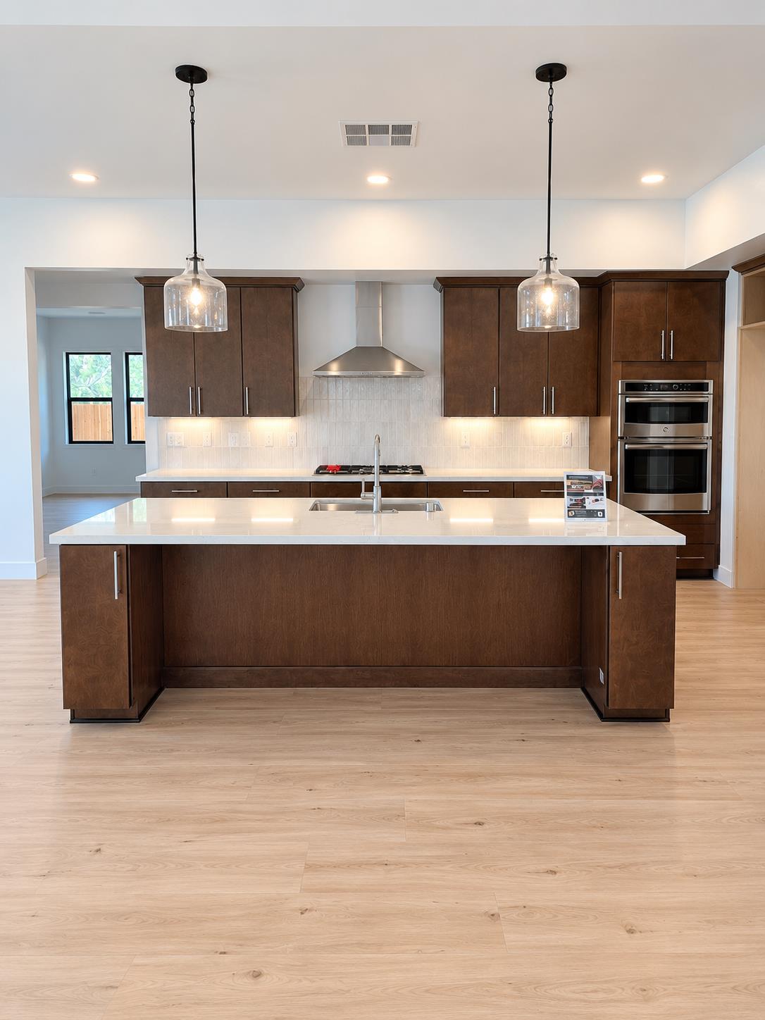 Kitchen with a large white island, dark wood cabinets, and stainless steel double ovens.