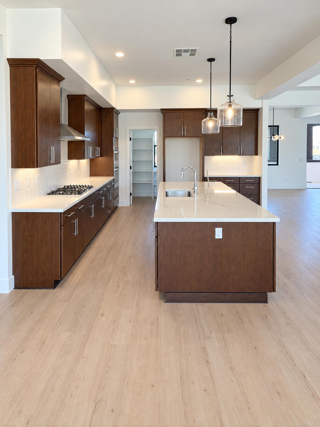 Kitchen with dark wood cabinets, a large white island, and pale wood floors.