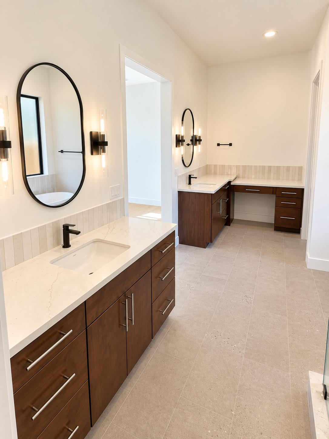 Bathroom with double dark wood vanities, white stone counters, and arched mirrors.