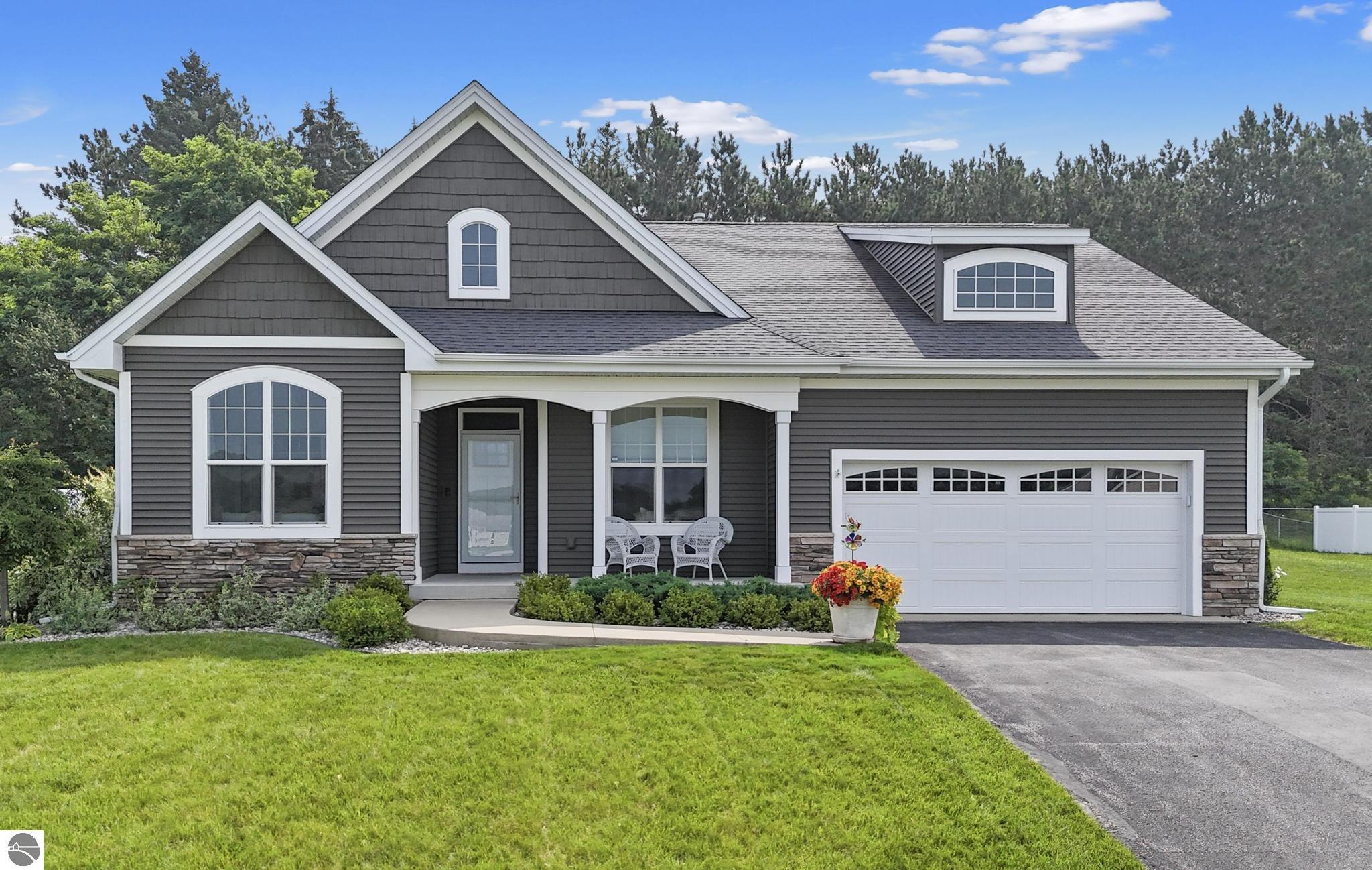 Gray gabled home with white trim, stone accents, attached garage, and covered porch.