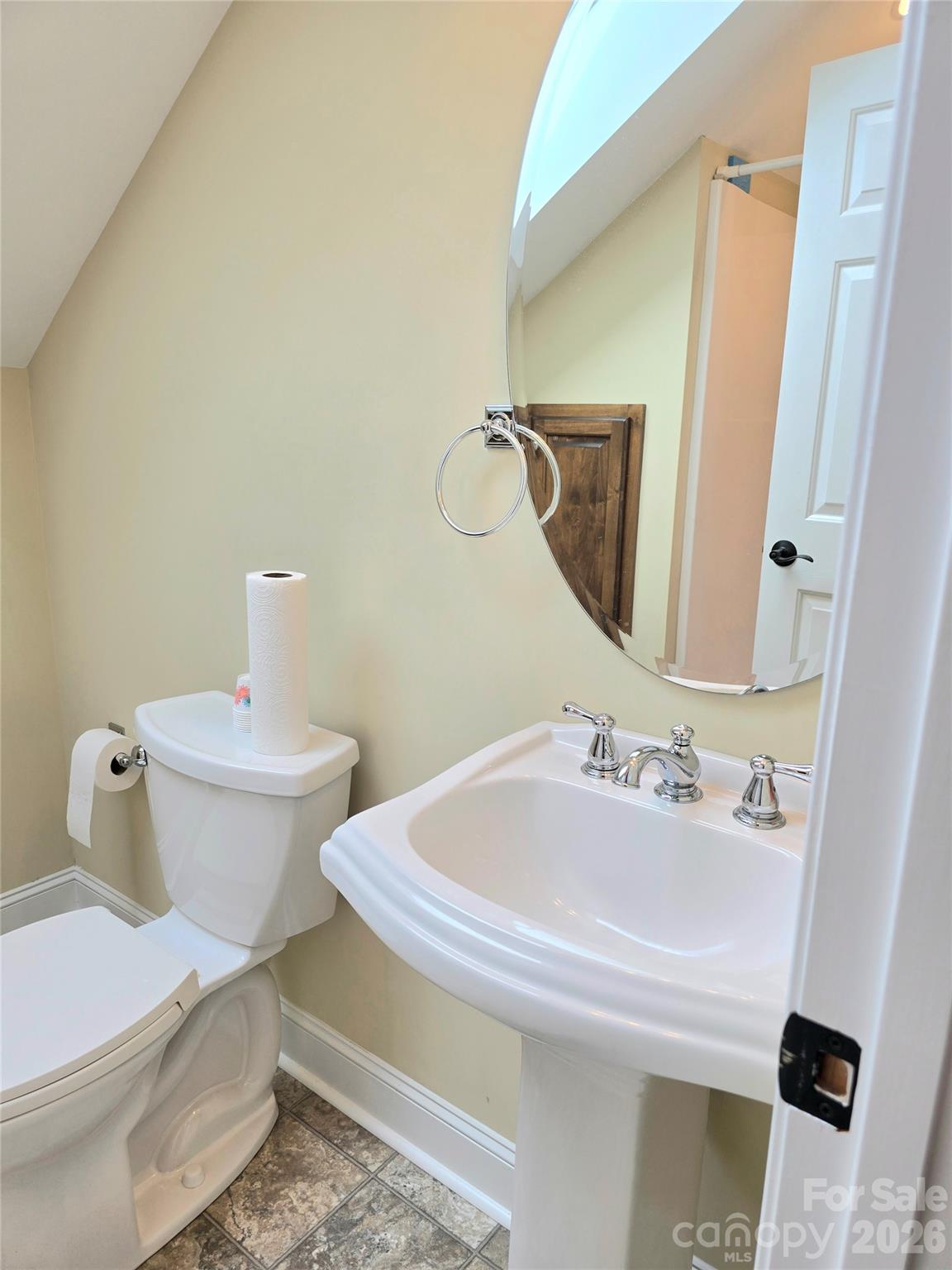 Small bathroom with a white sink and toilet beneath a sloped ceiling and skylight.