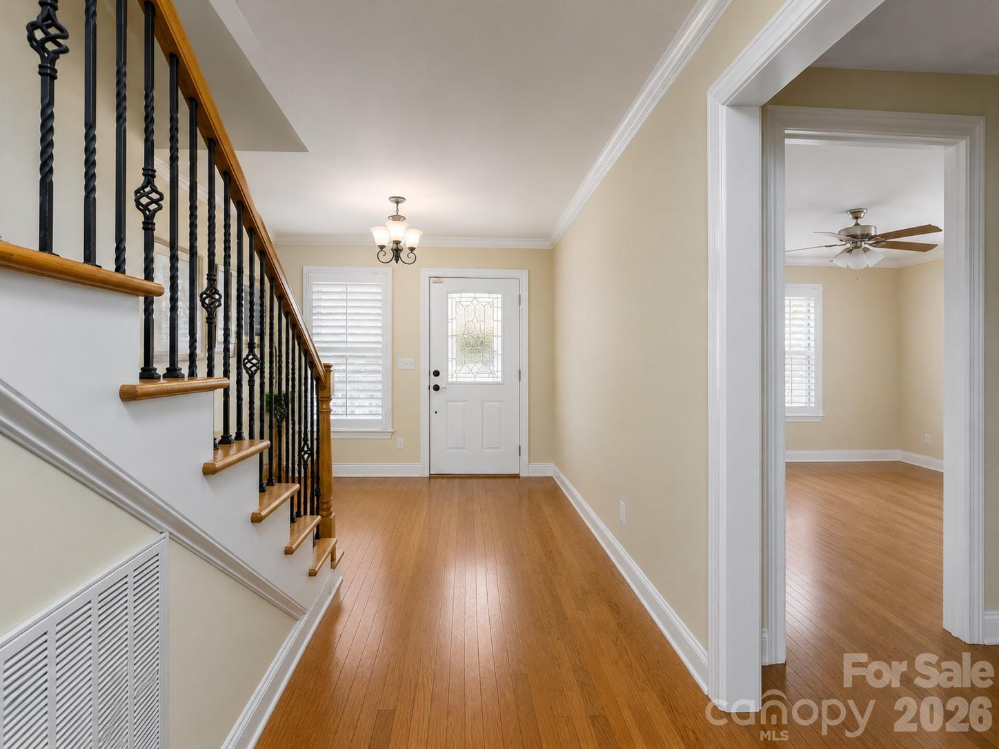 Entry hall with hardwood floors, an iron-baluster staircase, and a decorative-glass front door.
