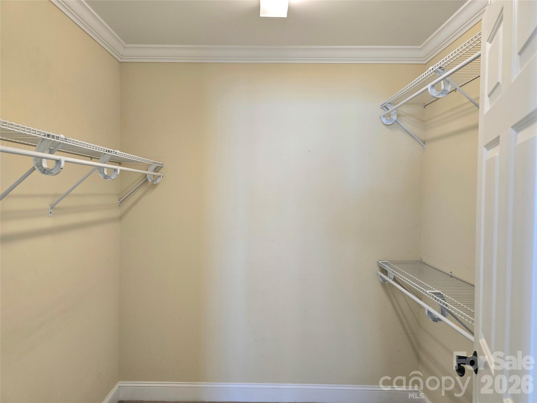Empty walk-in closet with white wire shelving on both sides.
