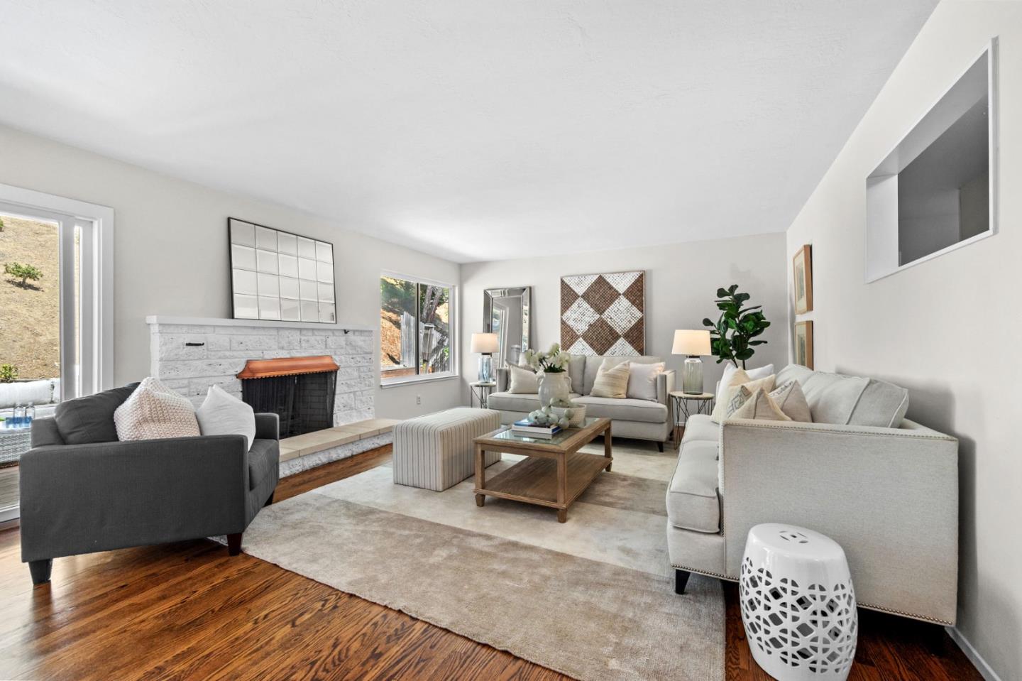 Staged living room with a white stone fireplace, neutral sofas, and hardwood floors.