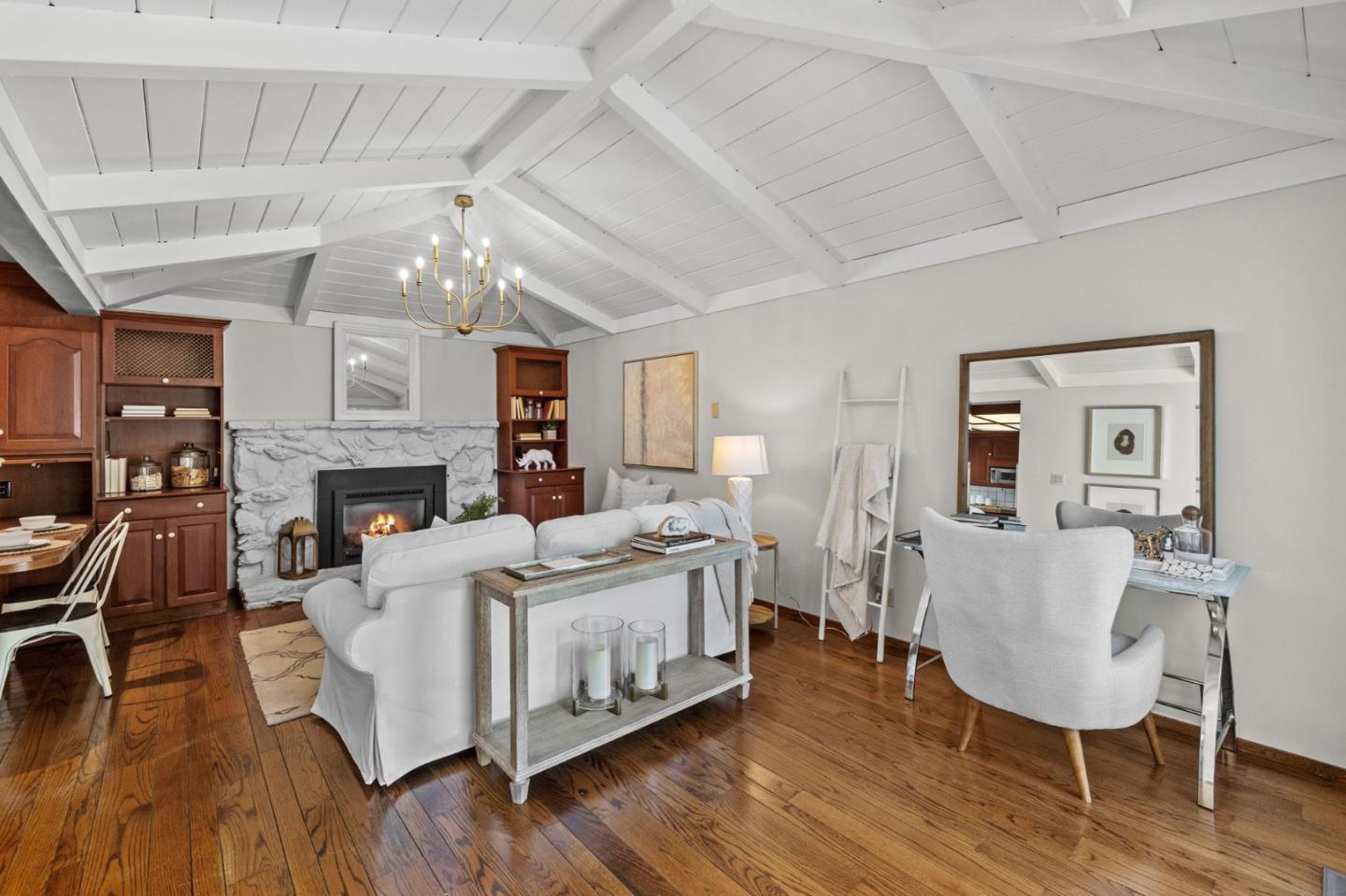 Living room with a vaulted beam ceiling, stone fireplace, dark wood built-ins, and hardwood floors.