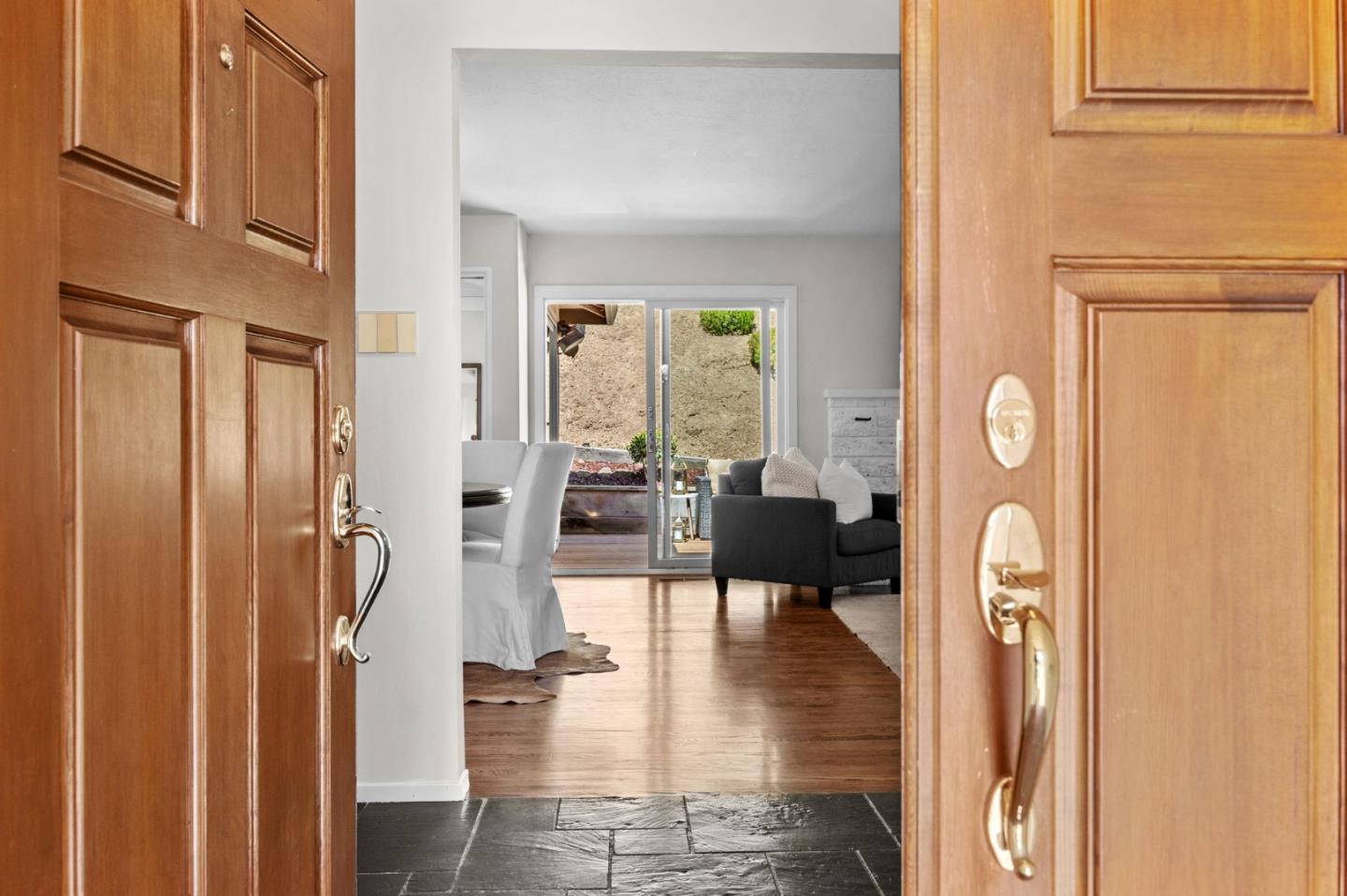 Open front door reveals a slate entry, hardwood floors, and a furnished living and dining area.