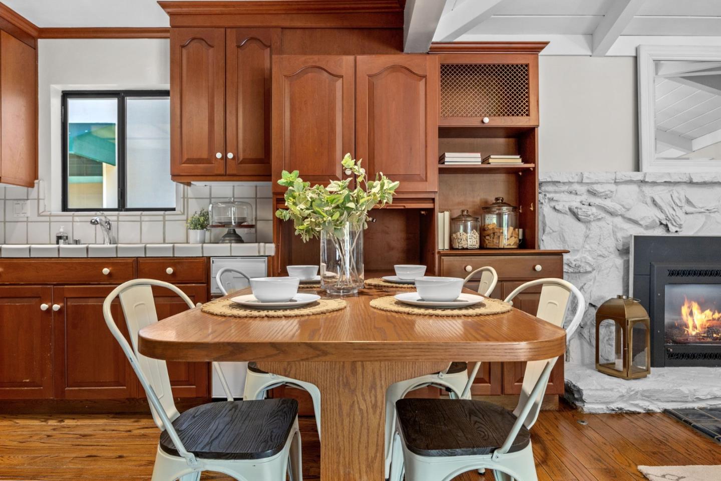 Dining area with a wooden table, dark wood cabinetry, and a stone fireplace.