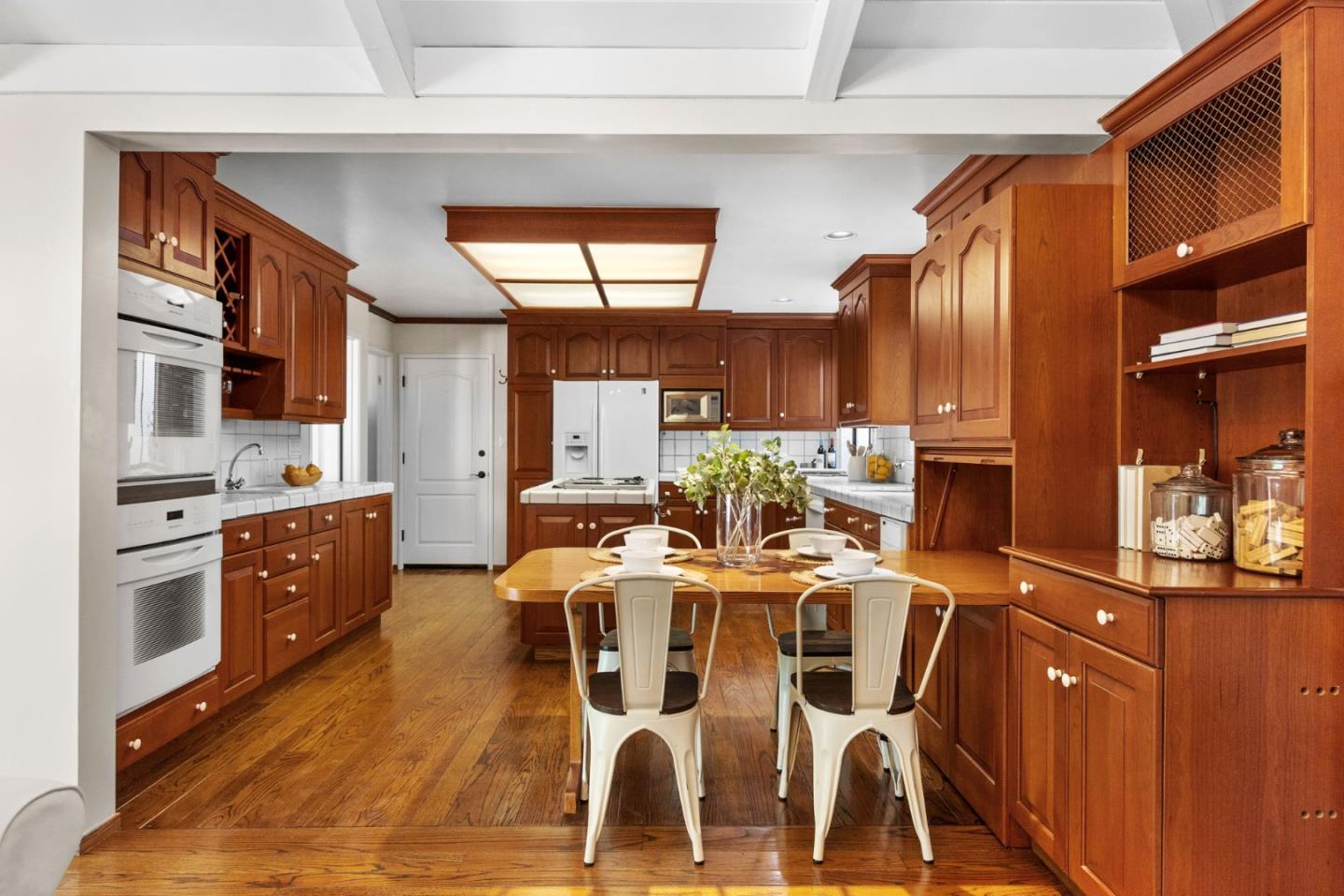 Kitchen with extensive cherry cabinetry, hardwood floors, and a central dining table.