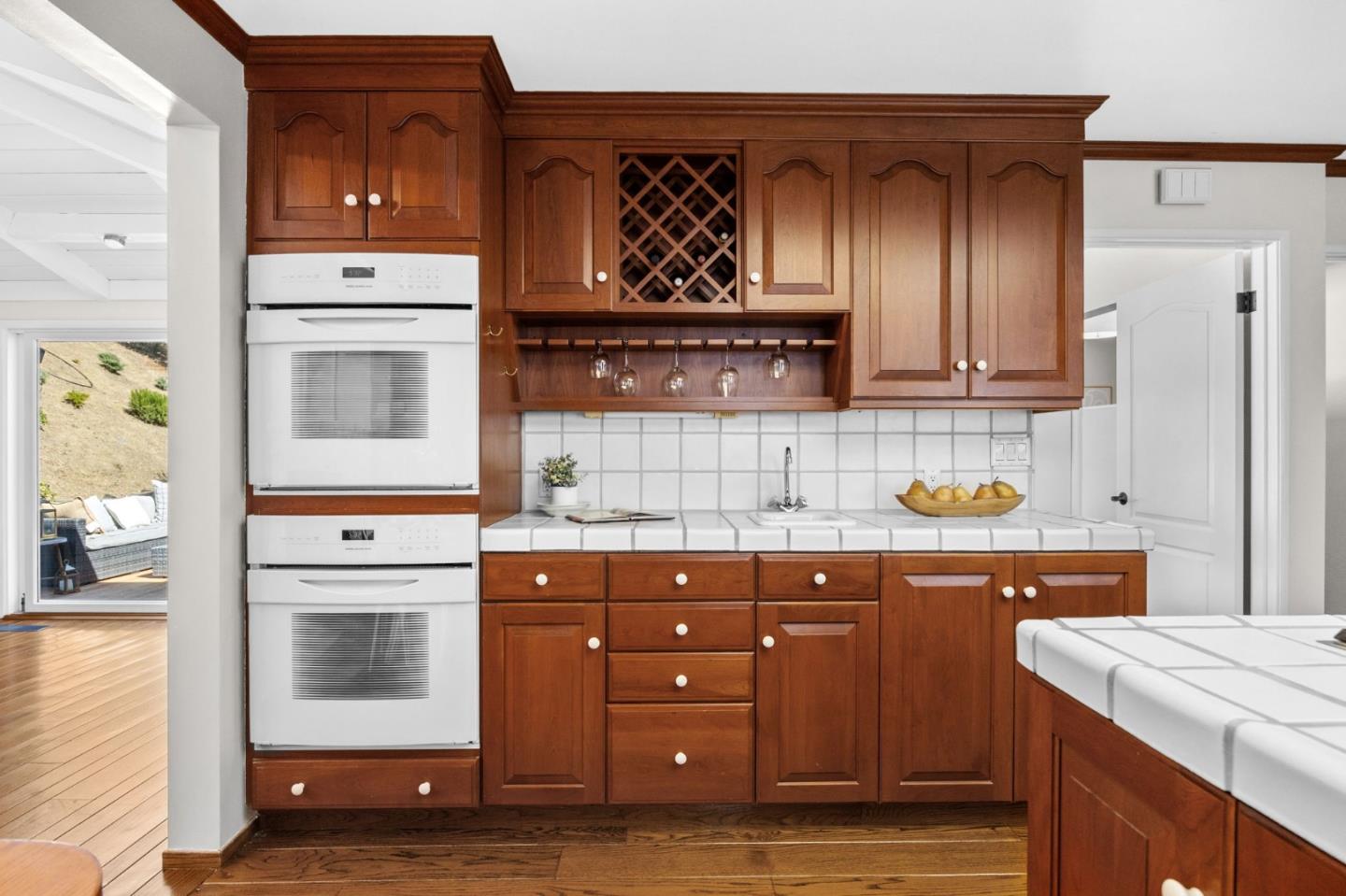 Kitchen with rich wood cabinetry, stacked wall ovens, and a built-in wine rack.