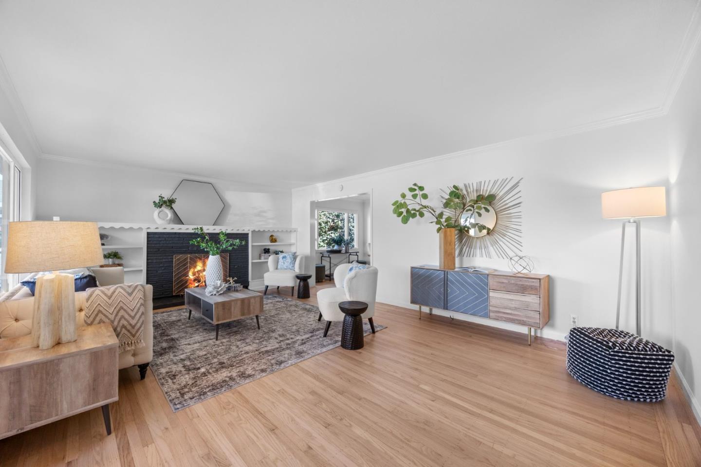 Staged living room with a lit fireplace, built-in shelving, and light hardwood floors.