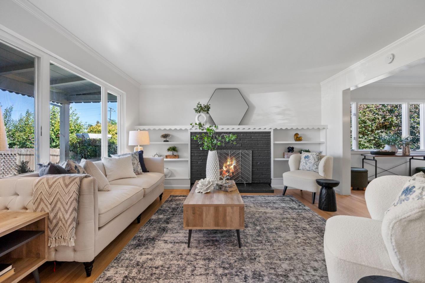 Living room with a lit brick fireplace, built-in shelves, and large windows.