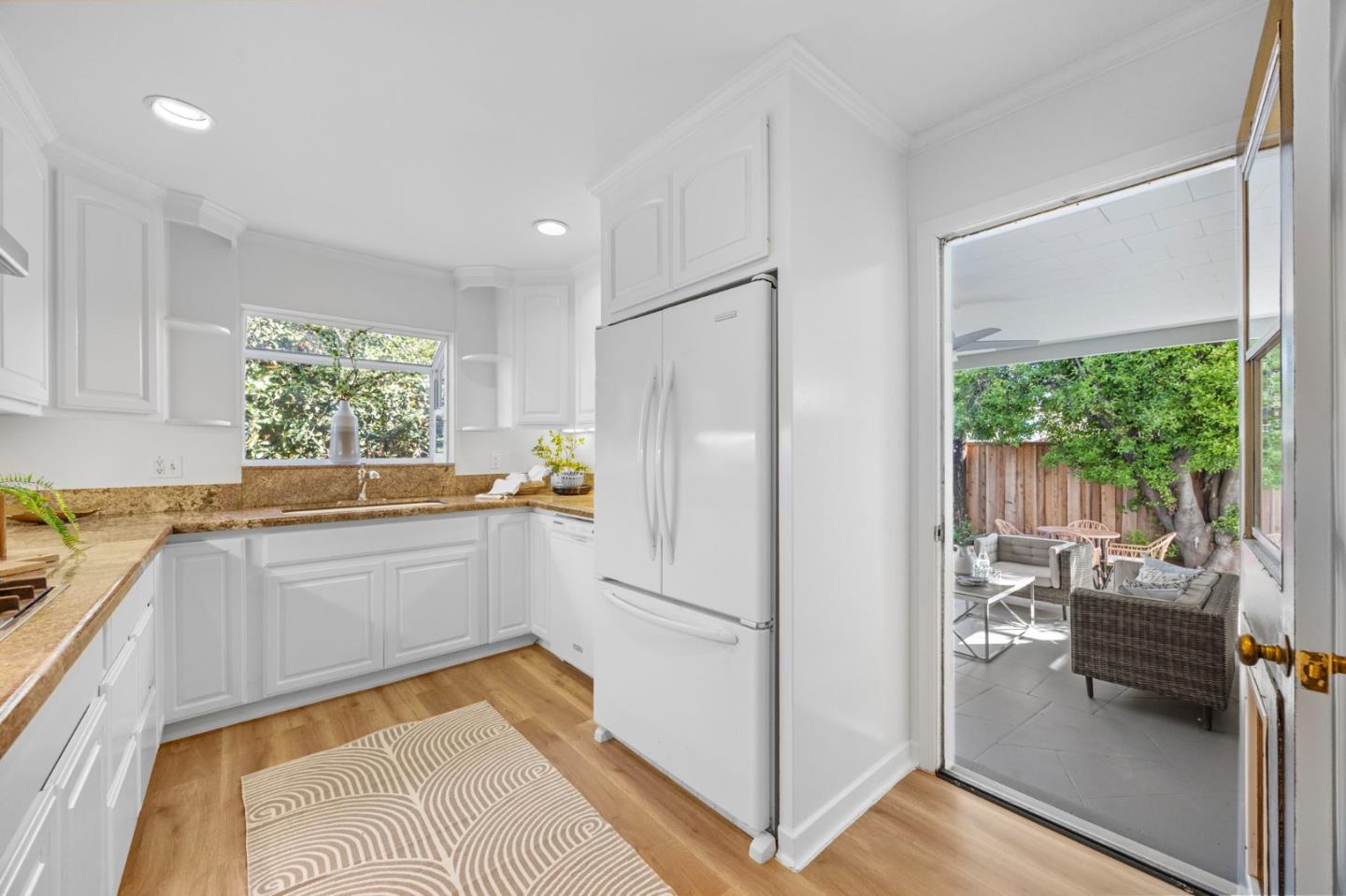 White kitchen with granite counters and an open doorway to a furnished patio.