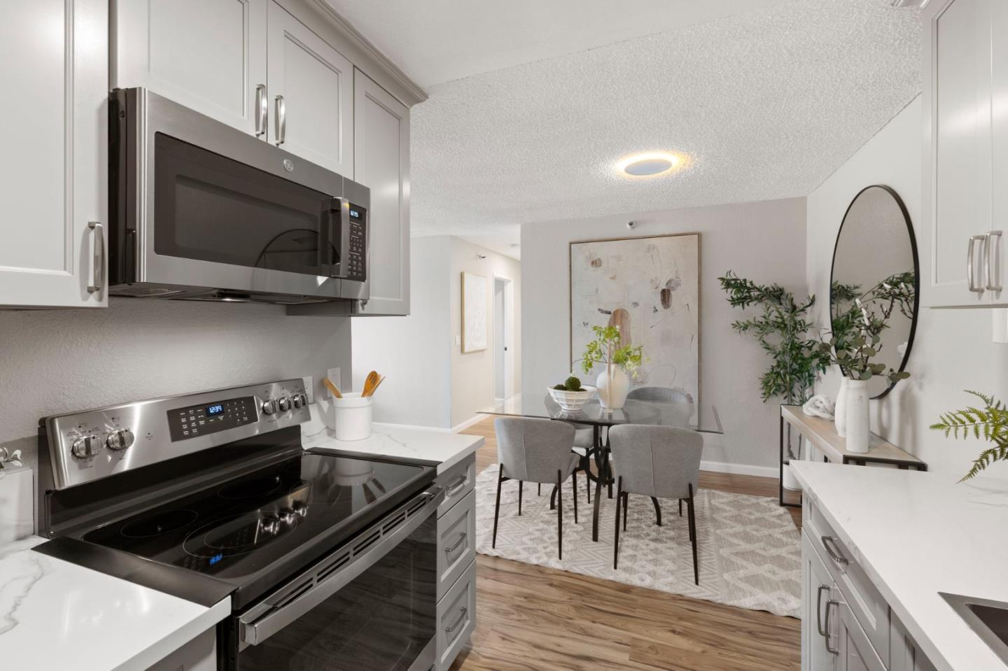 Staged kitchen with stainless steel appliances opening onto a glass dining area.