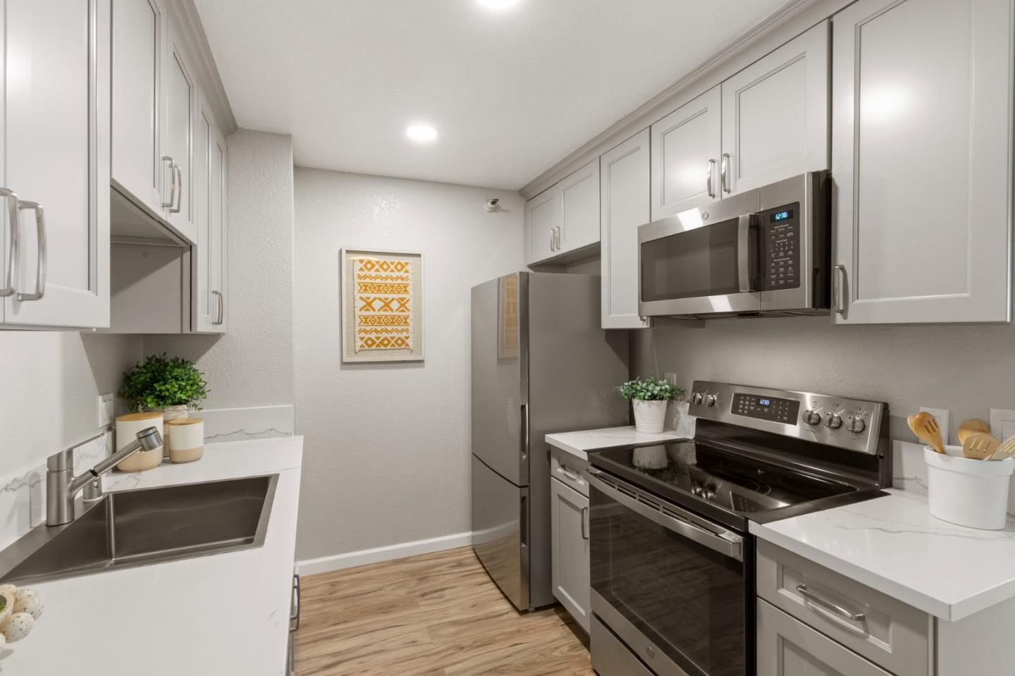 Kitchen with white cabinets, stainless steel appliances, and light wood flooring.