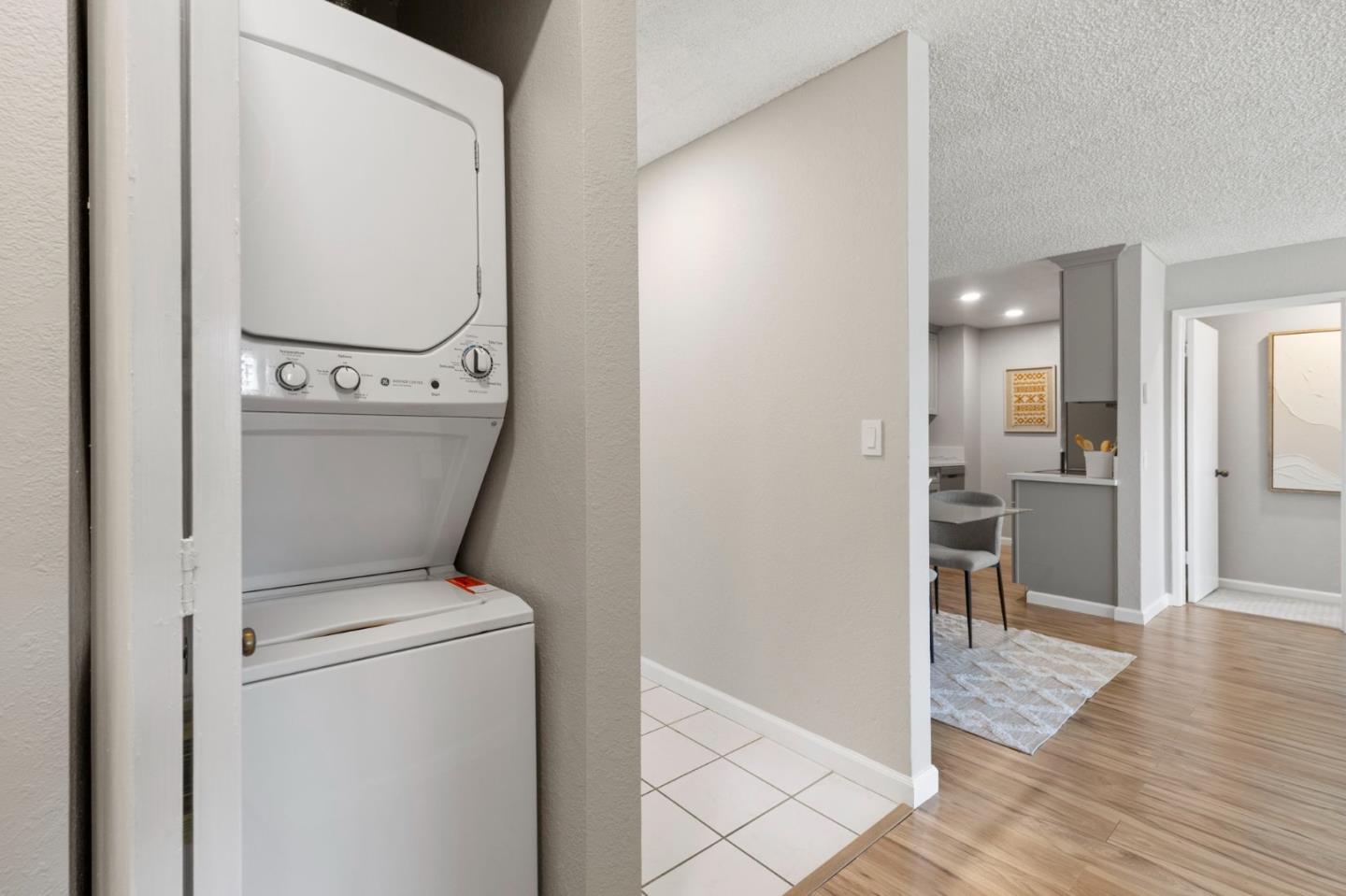Stacked washer and dryer in a laundry closet beside the kitchen and dining area.