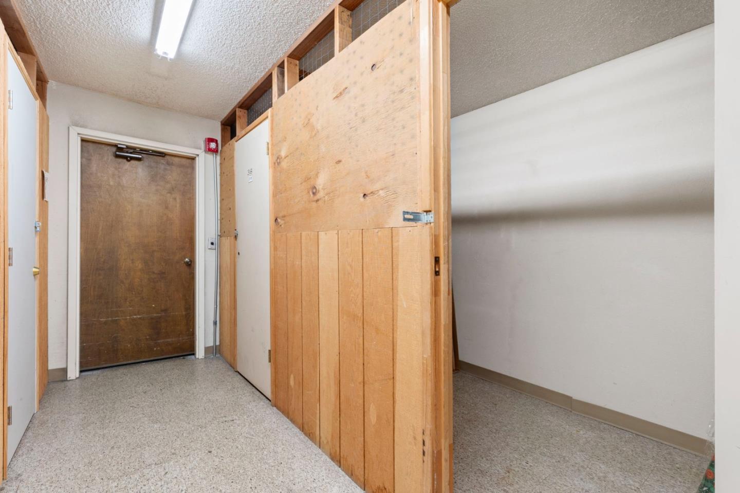 Interior hallway with a tall wooden partition, speckled flooring, and a brown door.