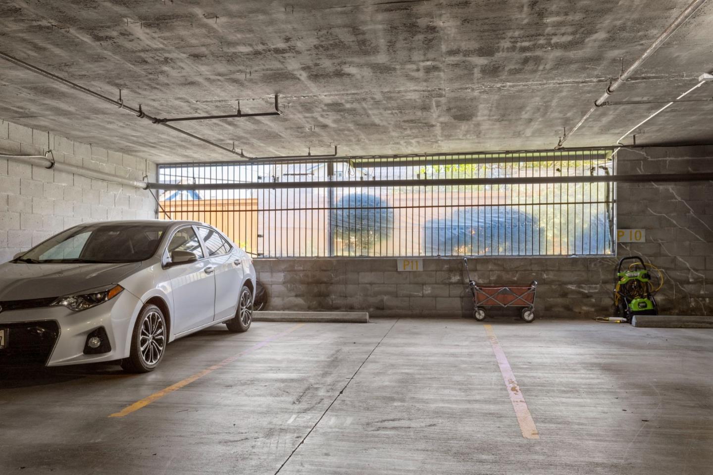 Parking garage with a white car beside marked spaces P10 and P11.