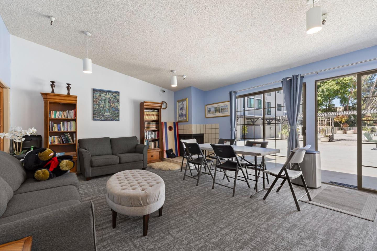 Furnished living and dining area with gray sofas and sliding glass doors opening to a patio.