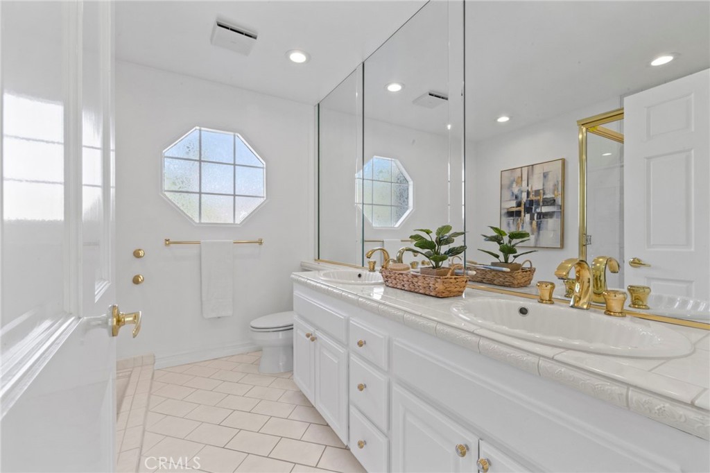 Bright bathroom with a double vanity, gold fixtures, and an octagonal window.