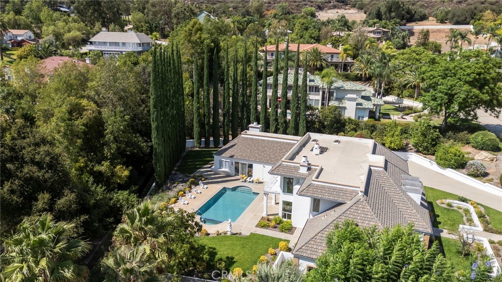 Aerial view of a home with a swimming pool and tall cypress trees.