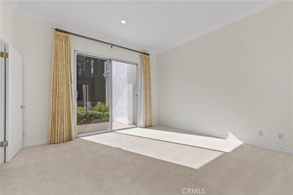 Vacant carpeted room with yellow curtains and a sliding glass door to a patio.