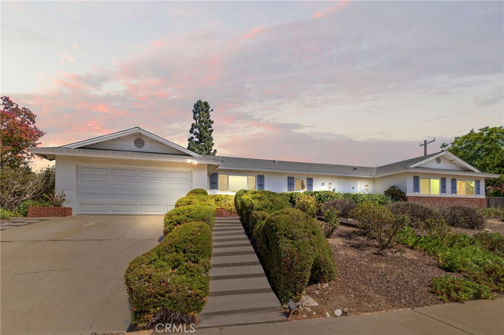 Single-story home with a two-car garage and landscaped walkway at dusk.
