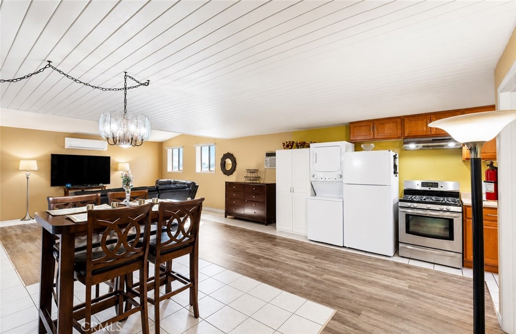 Open-plan kitchen and dining area with wood cabinets, stainless steel range, and white laundry appliances.
