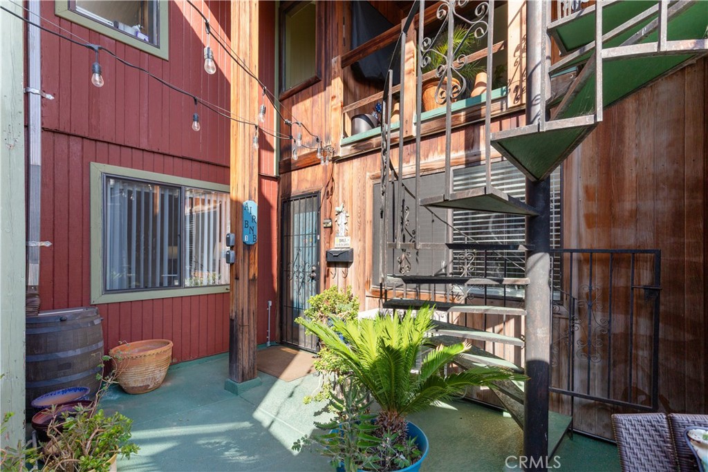 Exterior courtyard with an ornate spiral staircase, red siding, and potted plants.